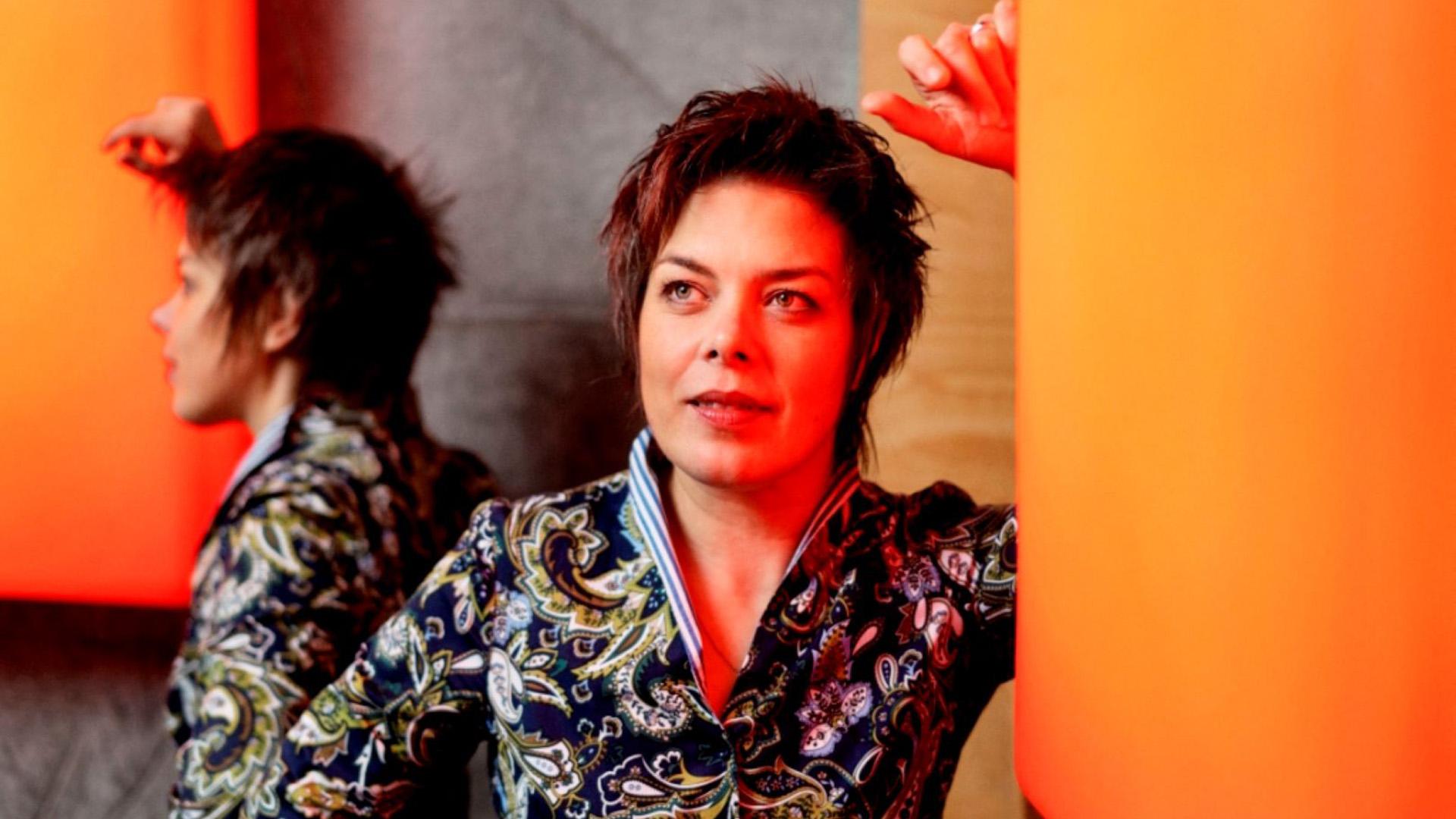 Martina Batič står lutad mot en orange vägg.